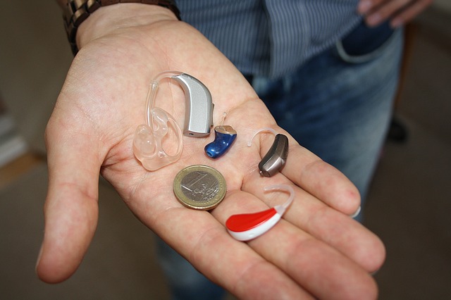 a person comparing the sizes of euro coin and different hearing aids