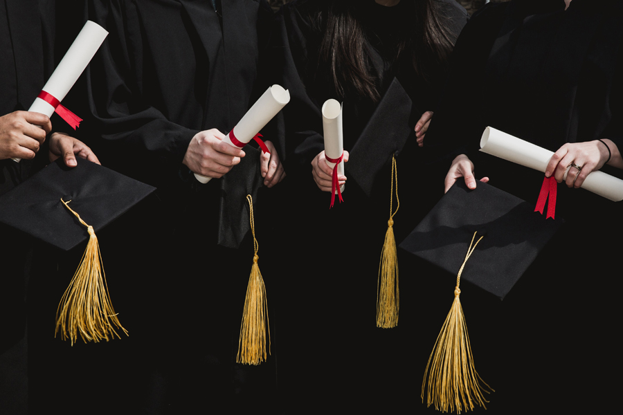 newly graduates holding a diploma and a graduate cap